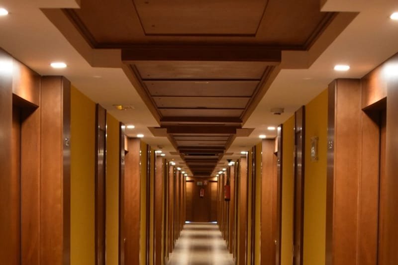 Couloir d’hôtel desservant plusieurs chambres : les punaises de lit se propagent d’une chambre à l’autre par les plinthes et les gaines